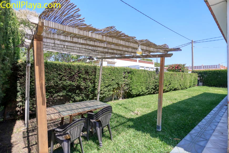 Jardín con pérgola y mesa de exterior visto desde la terraza.