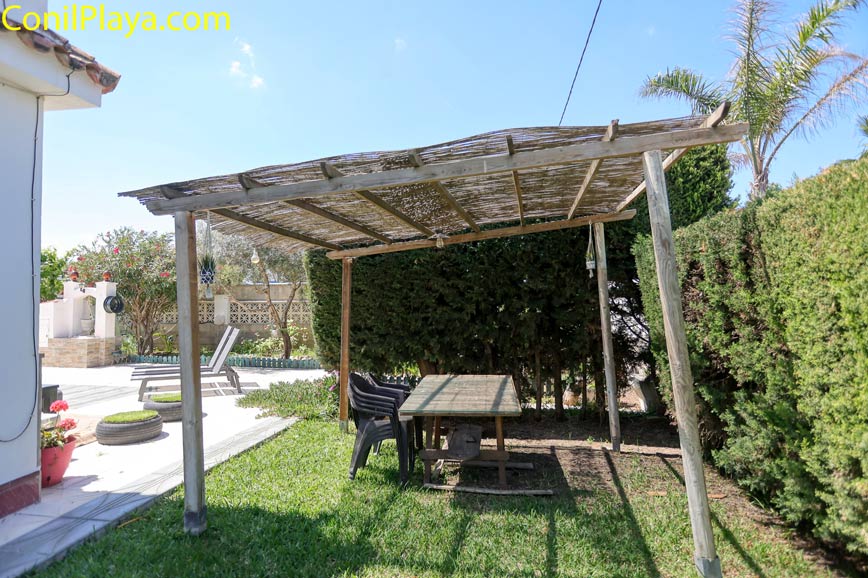 Pergola de madera con mesa y sillas en jardín junto al alojamiento