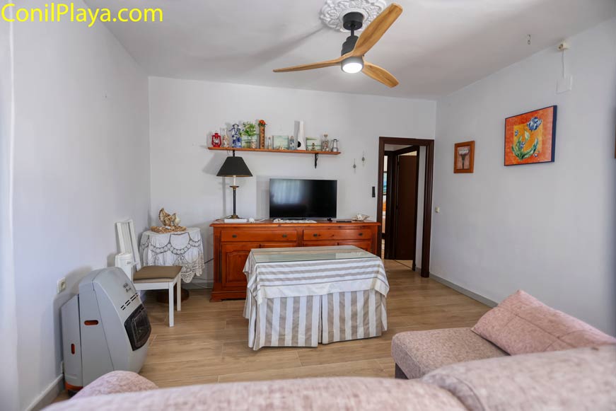 Salón acogedor con sofá, televisor, mueble y ventilador de techo