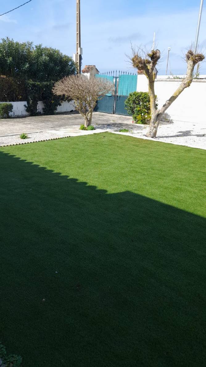 Cancela metálica del aparcamiento y césped artificial