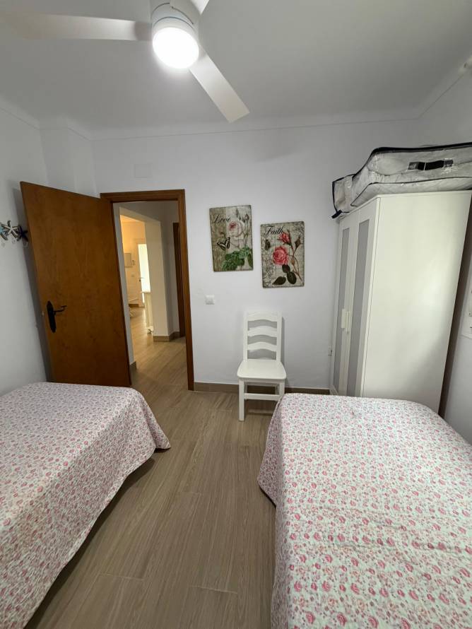 Dormitorio con dos camas individuales armario y ventilador de techo encendido