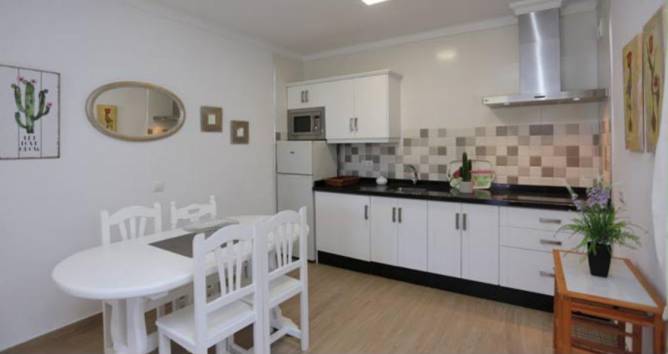 Cocina con mesa de comedor y muebles blancos vista desde la entrada