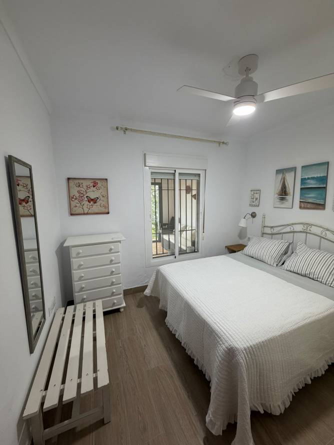 Dormitorio con ventilador de techo y cama doble decorado en blanco