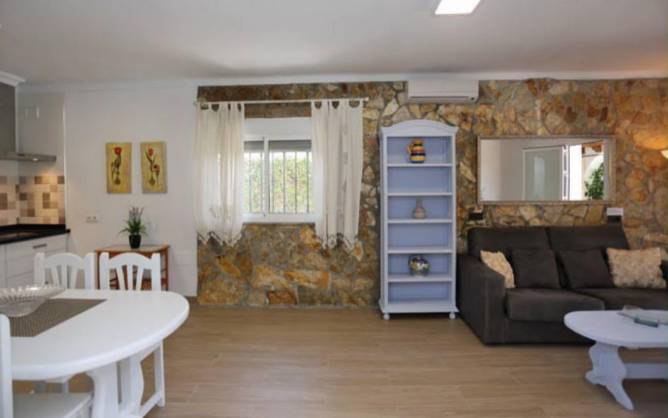 Salón amplio con sofá oscuro y pared de piedra natural