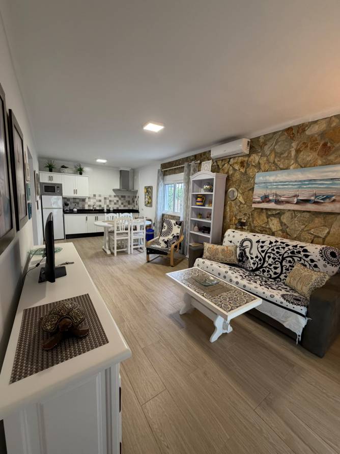 Salón decorado con sofá y mesa de centro junto a cocina integrada al fondo