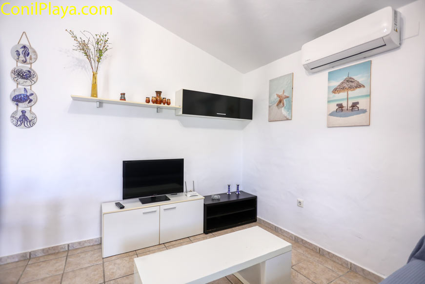 Salón luminoso con aire acondicionado y decoración costera en pared blanca