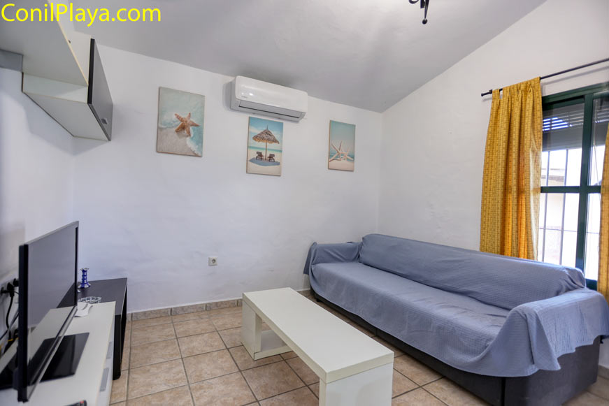 Vista del salón con sofá, televisión y aire acondicionado