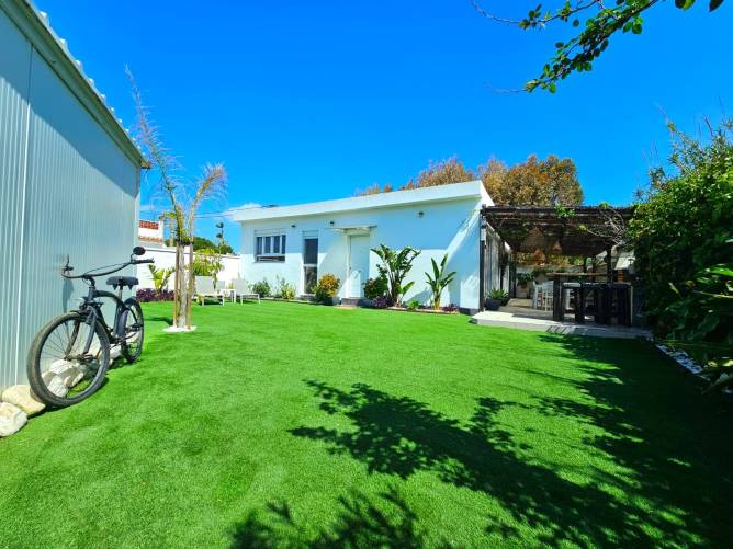 Exterior de la casa cerca de la playa Fachada de casa vacacional blanca con jardín y bicicleta