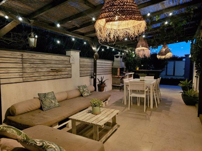 Ambiente nocturno acogedor en el porche Sofás exteriores bajo lámparas de mimbre encendidas de noche