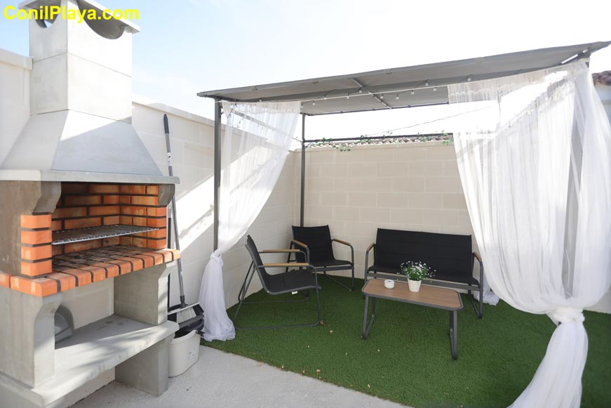 zona exterior con barbacoa y pérgola junto a una cabaña de madera en alquiler