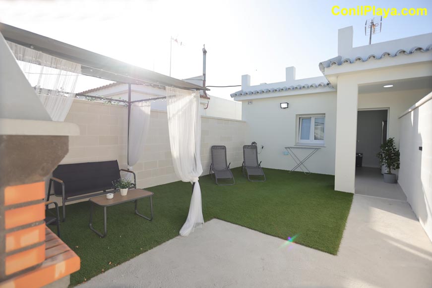 Jardín privado con césped artificial, zona de relax y entrada a la vivienda