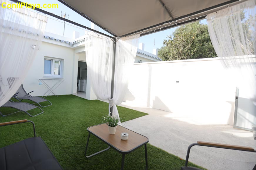Pèrgola con cortinas blancas y muebles exteriores en la casa de El Palmar de Vejer