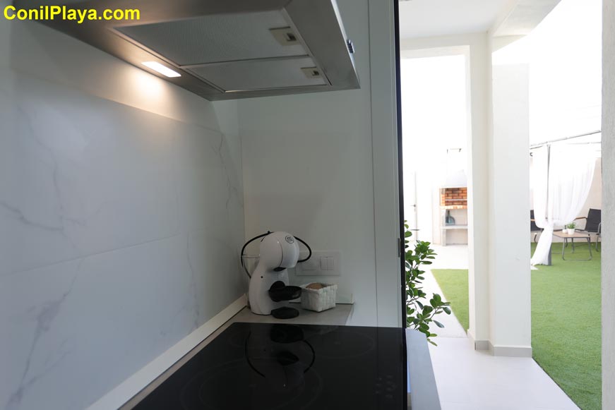 Cocina moderna con cafetera blanca junto a zona exterior con césped