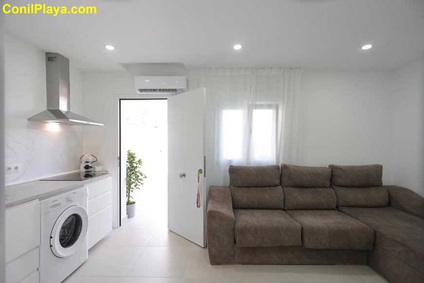 Salón con sofá chaise longue y cocina integrada moderna