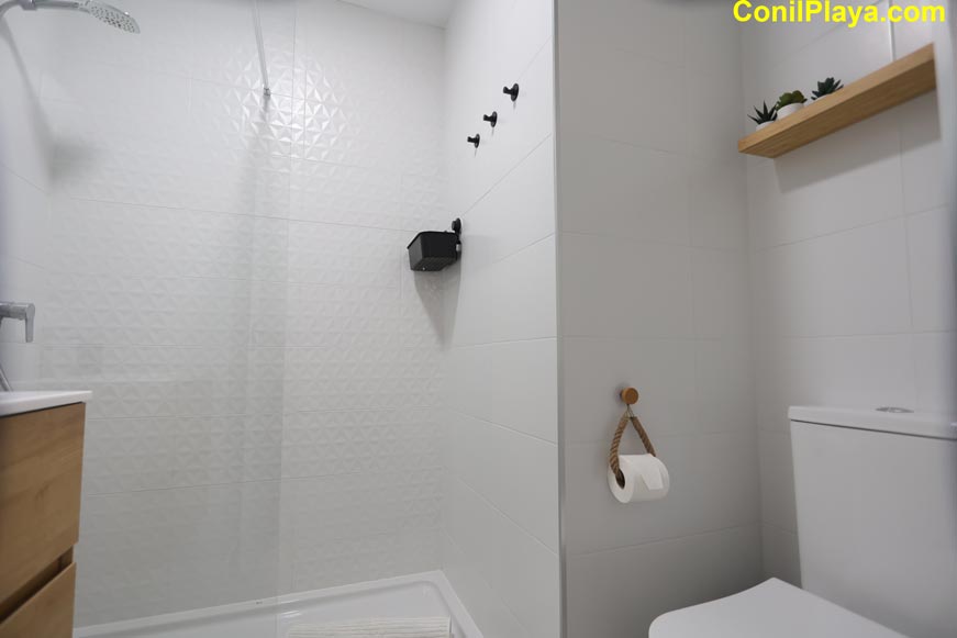 Perspectiva del cuarto de baño con ducha de pared blanca y sanitario