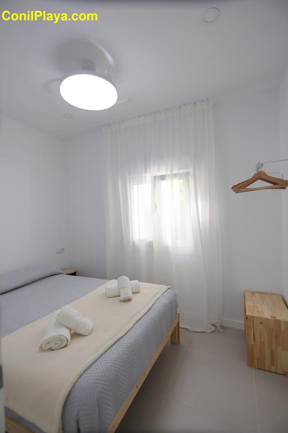 Dormitorio principal con cama doble, ventana y ventilador de techo moderno