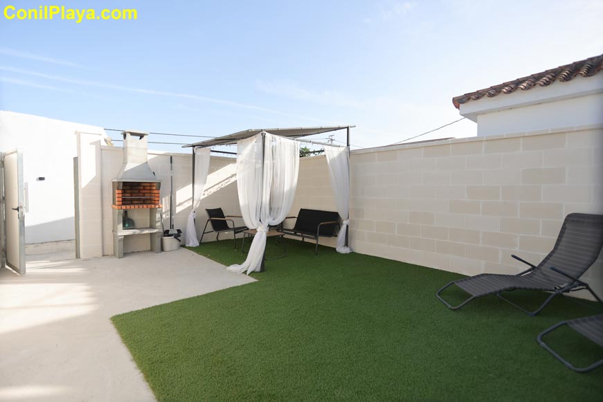 Zona de jardín con barbacoa, pérgola y mobiliario de exterior