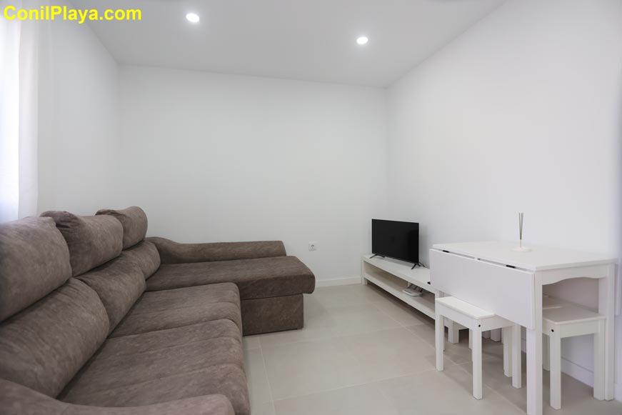 Salón moderno con sofá chaise longue y mesa pequeña junto a la ventana