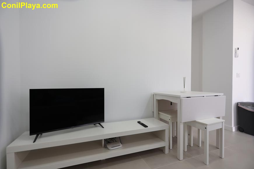 Mesa comedor blanca y televisor en salón minimalista