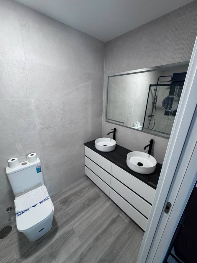 Cuarto de baño moderno con doble lavabo y suelo de imitación madera