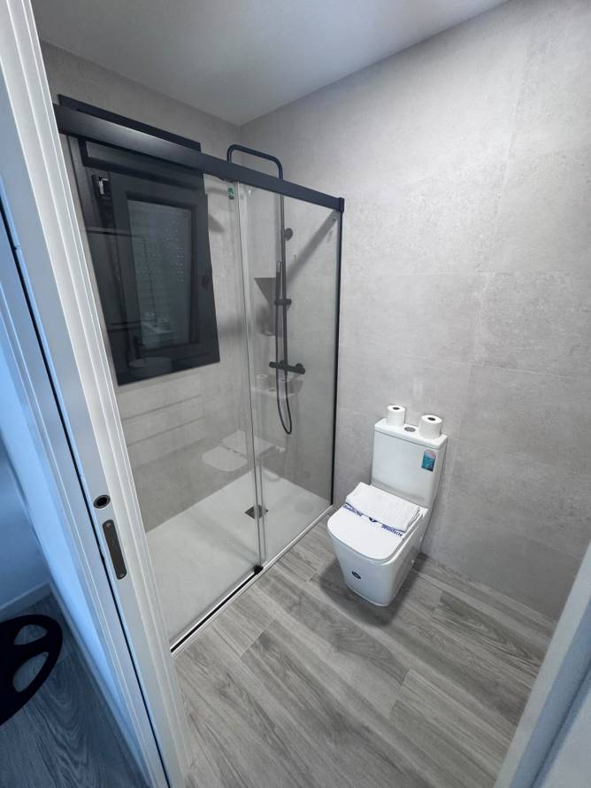 Cuarto de baño moderno con ducha y ventana visto desde la puerta
