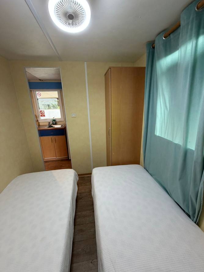 Dormitorio interior con armario, dos camas y ventana con cortina azul