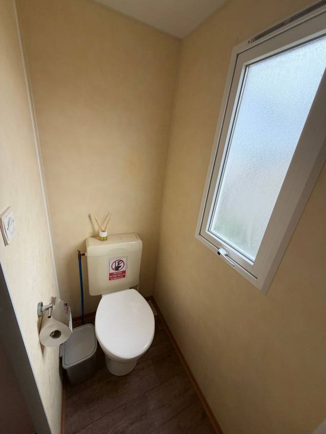 Aseo pequeño con ventana, inodoro, papel higiénico y cubo de basura