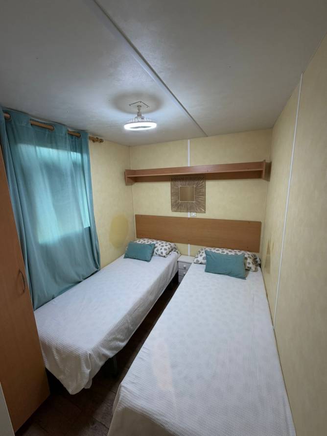 Dormitorio con dos camas individuales y ventana con cortina azul