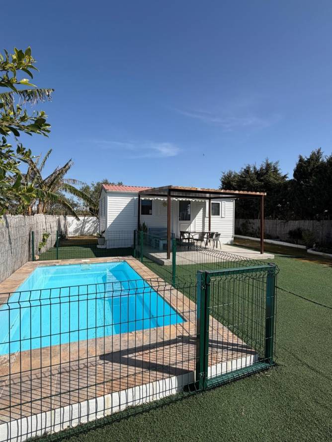 Piscina privada vallada junto a casa bungalow y terraza exterior soleada