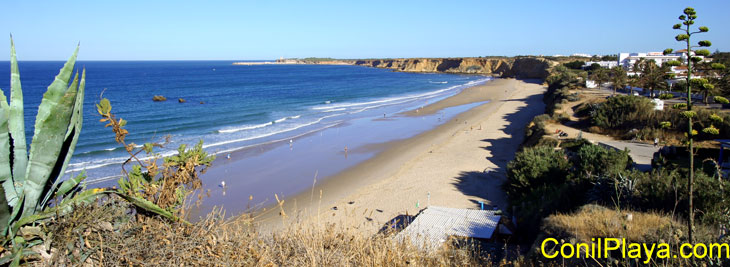 Vista de la playa desde lo alto de los acantilados. En medio del mar se encuentra las 3 piedras, al fondo en el horizonte el Puerto de Conil. A la derecha, la urbanización La Fuente del Gallo.