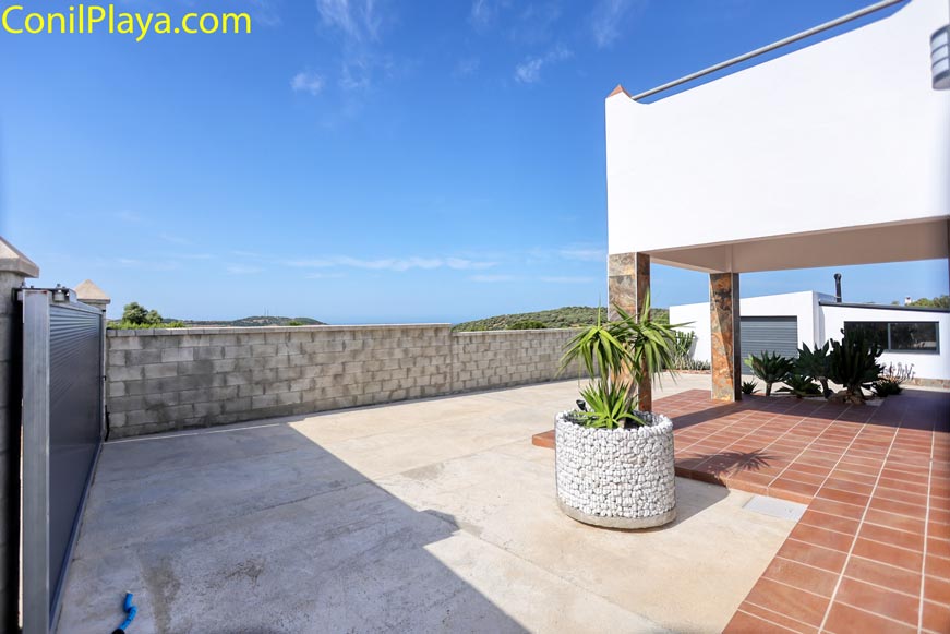 Aparcamiento amplio junto a una vivienda y un porche con plantas decorativas