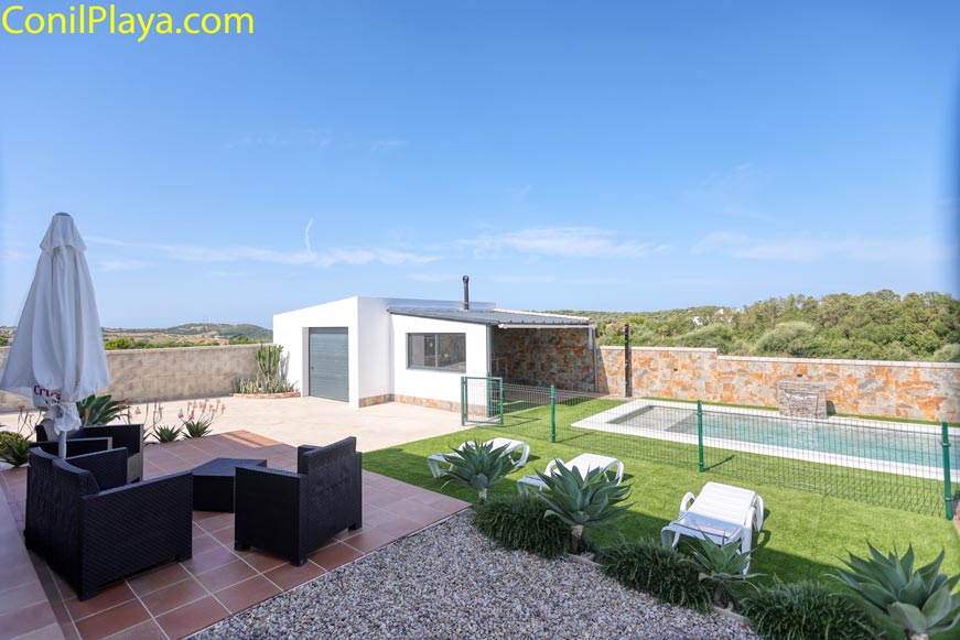 Zona exterior con asientos junto a la piscina privada y césped artificial