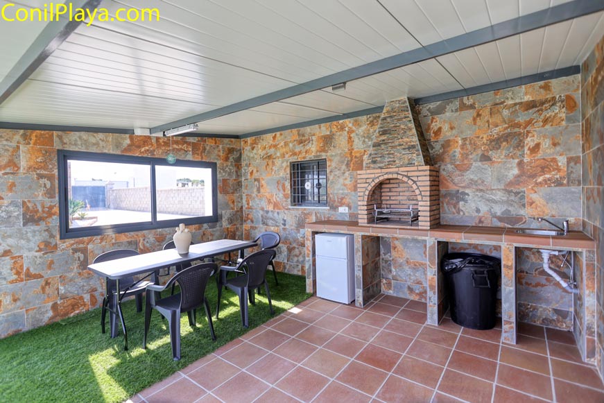 Porche cubierto con barbacoa de obra, mesa y varias sillas