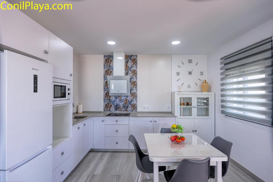 Cocina moderna luminosa con mesa de comedor y mobiliario blanco