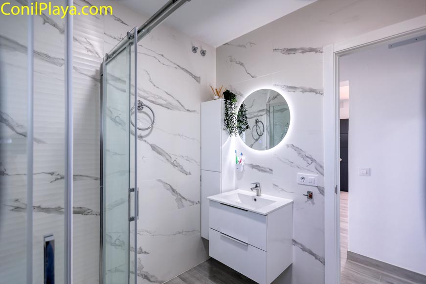 Cuarto de baño moderno con ducha y lavabo vistos desde la entrada