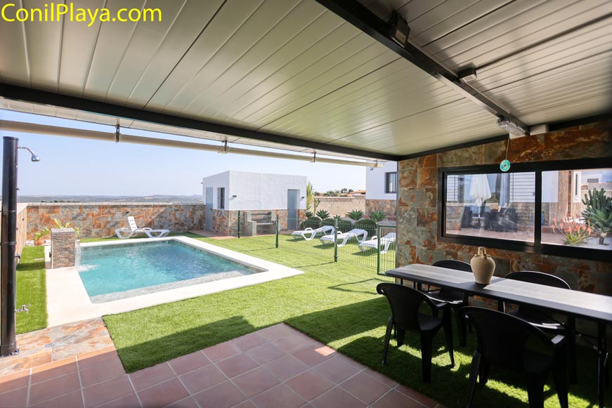 Vista desde el porche hacia piscina privada con tumbonas y mesa exterior