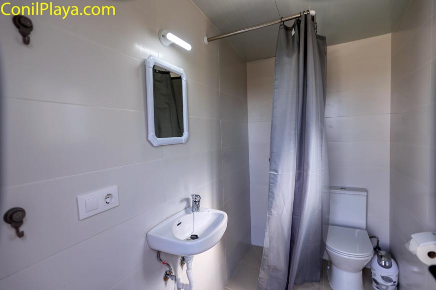 Cuarto de baño con ducha cortina lavabo y espejo desde la entrada