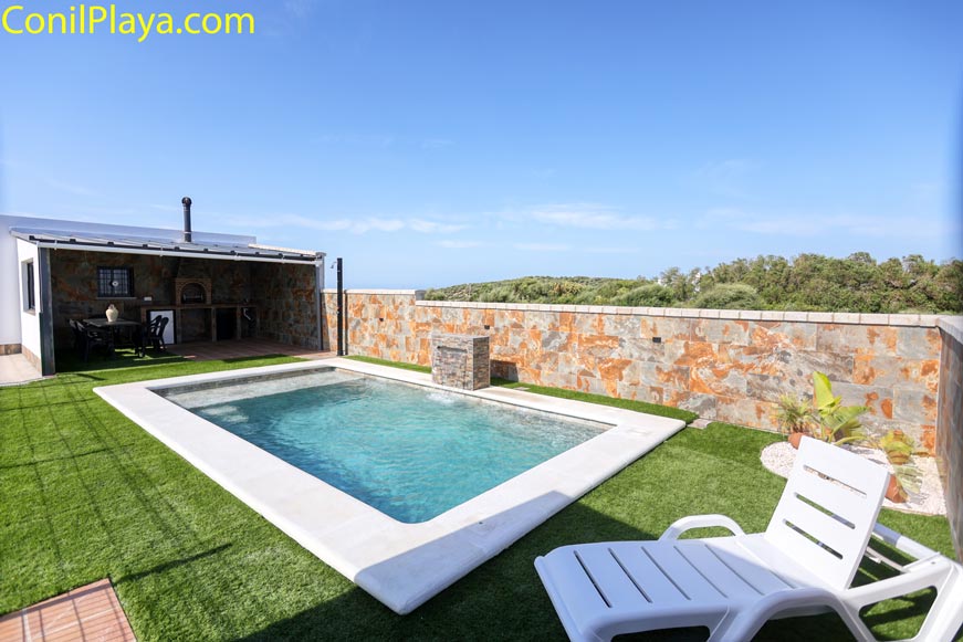 Piscina privada junto césped artificial y zona barbacoa desde la terraza