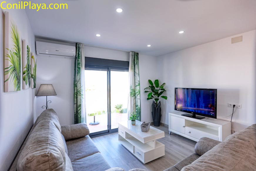 Aire acondicionado en salón con sofá gris y televisor