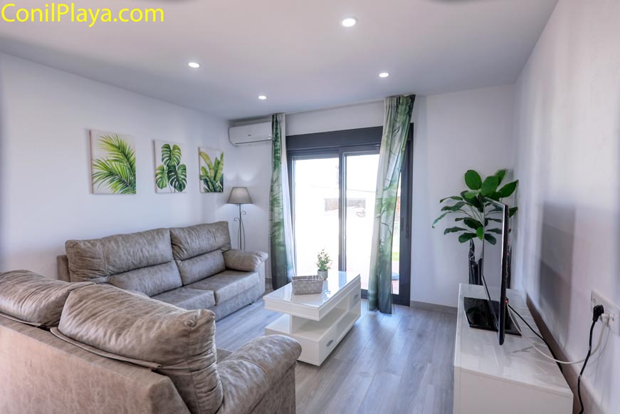 Salón moderno con sofá grande y televisor junto a ventanal