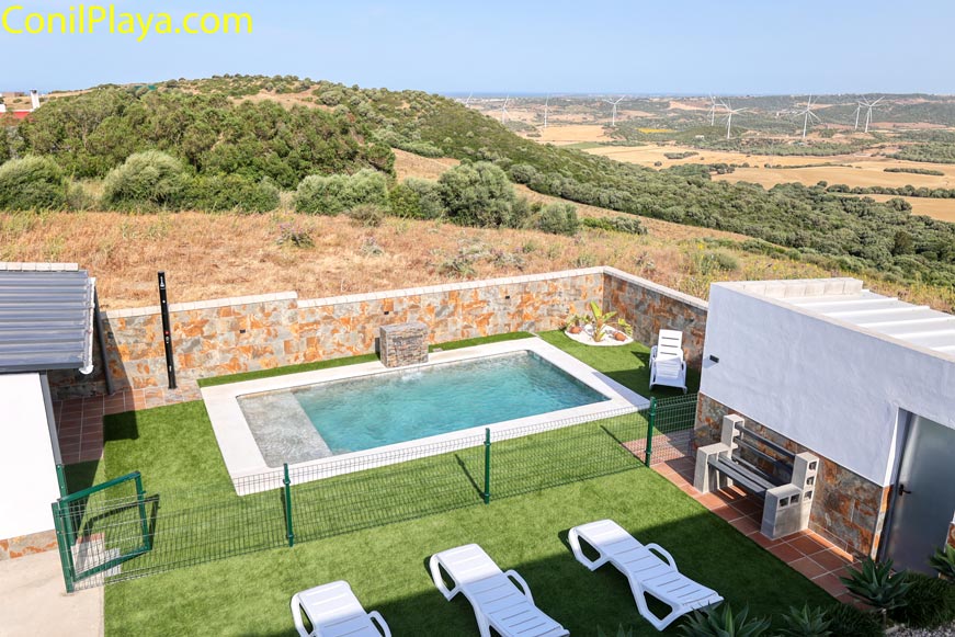 Zona de piscina privada con tumbonas y césped artificial junto a barbacoa