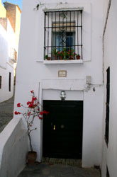 Casa típica de Vejer con el balcón repleto de macetas con geranios.