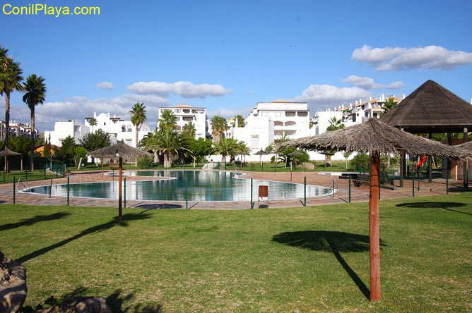 Jardín con césped y sombrillas con la piscina al fondo