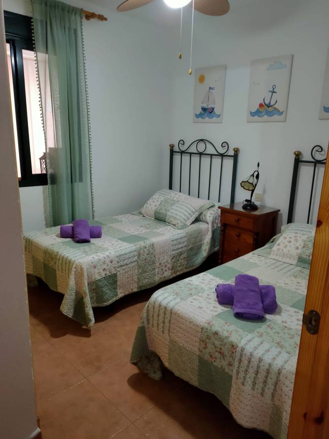 Dormitorio con dos camas individuales colchas estampadas y ventana lateral