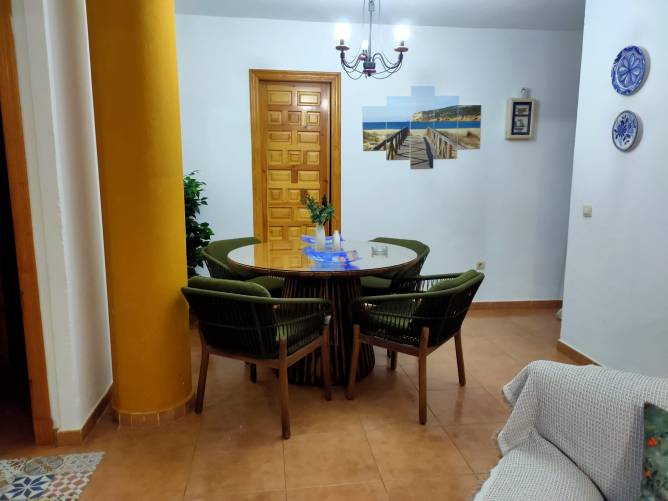 Comedor acogedor con mesa redonda y sillas verdes junto a puerta de madera