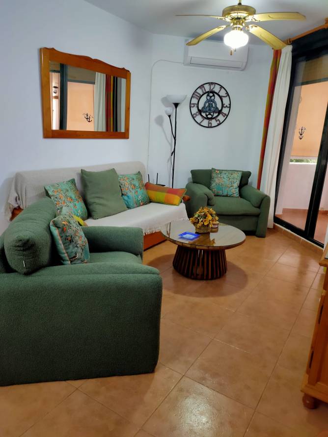 Salón con sofás verdes, mesa baja y acceso a terraza desde salón