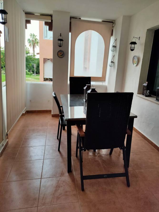Terraza con mesa de comedor y sillas cerca de ventana y vistas a jardín