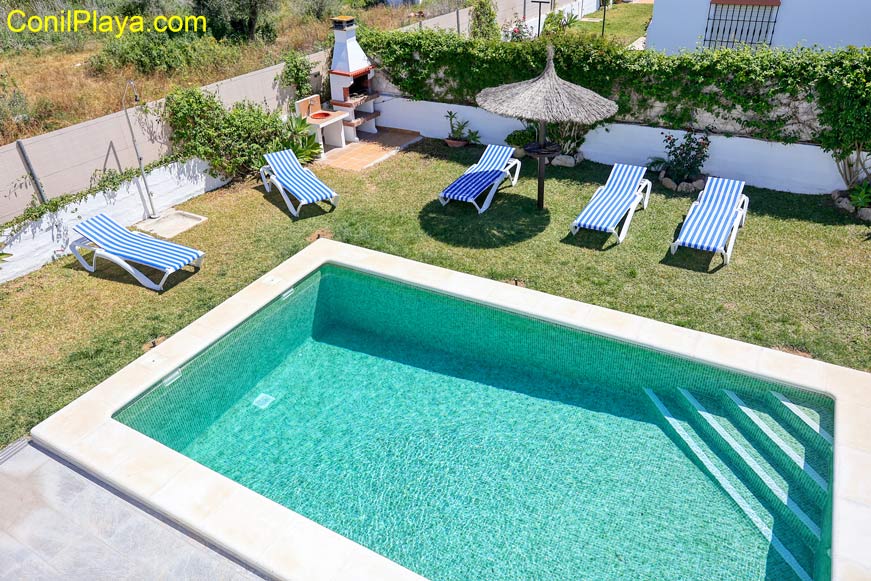 La piscina y la barbacoa al fondo a la izquierda.