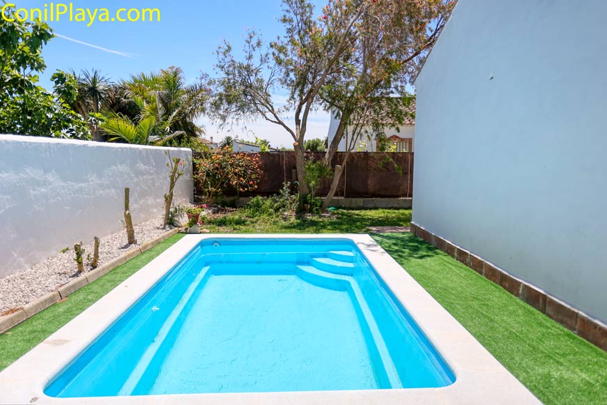 Piscina rectangular de obra al aire libre rodeada de césped artificial y árboles en un jardín privado