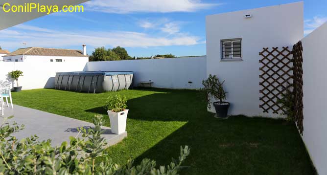 jardín con césped y piscina al fondo